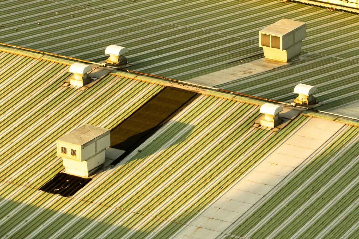 Rooftop ventilation units standing on a corrugated metal commercial roof