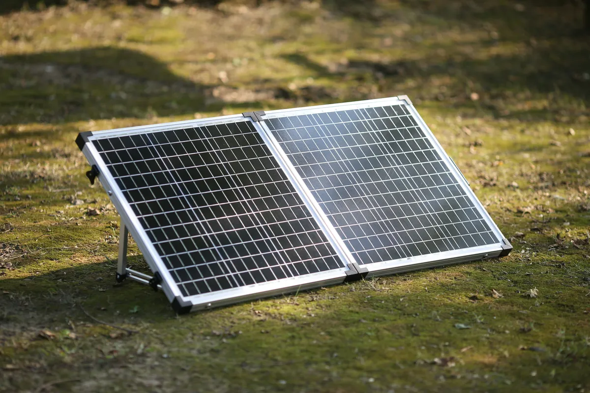 Folding portable solar panel propped up on a mossy lawn
