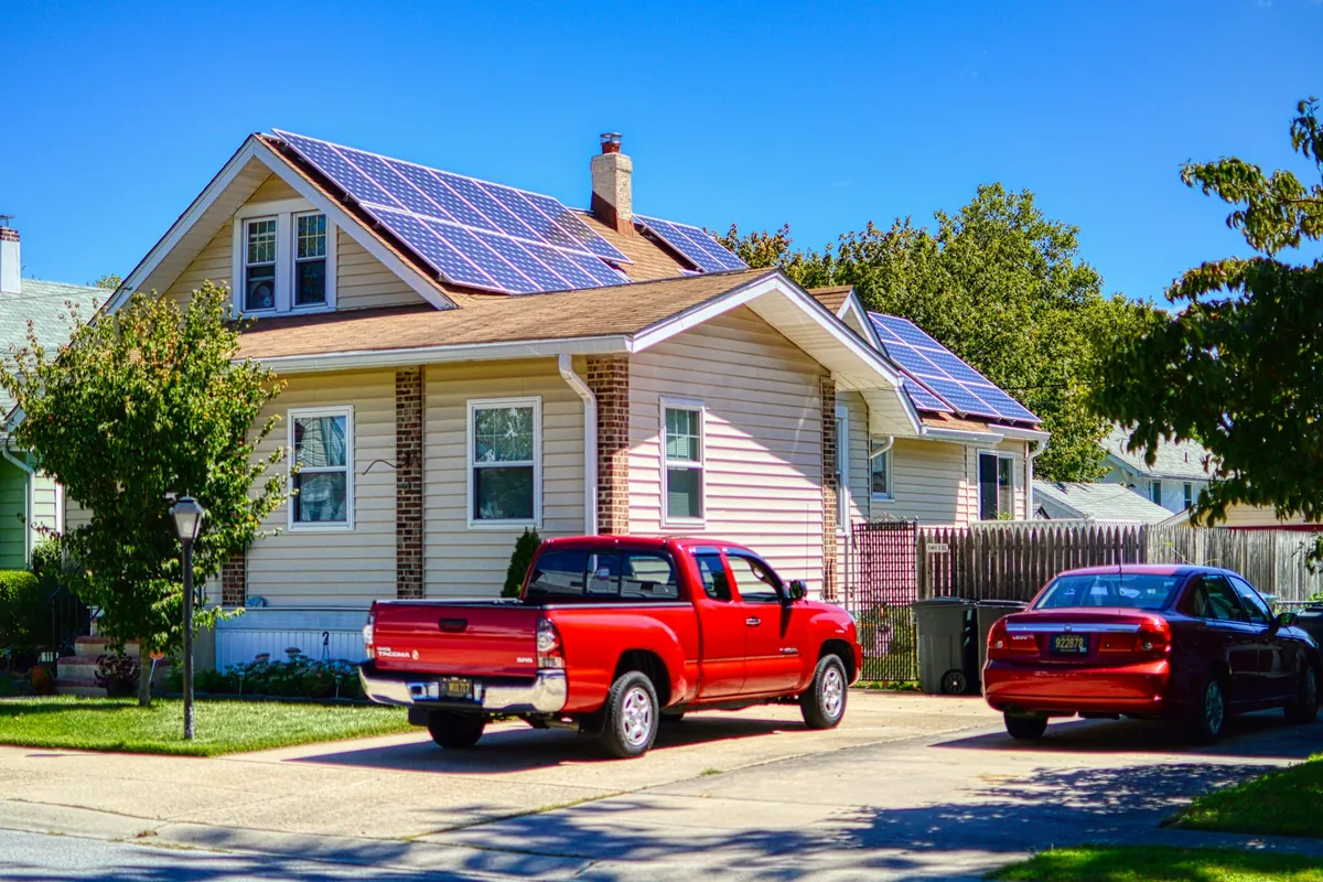 Craftsman-style house with a rooftop solar array and a red pickup truck in the driveway