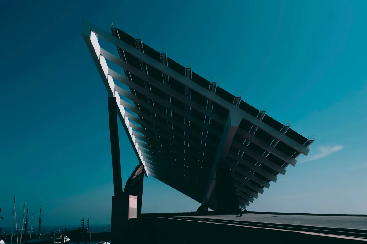 Tilted solar canopy structure seen from below against a deep teal sky