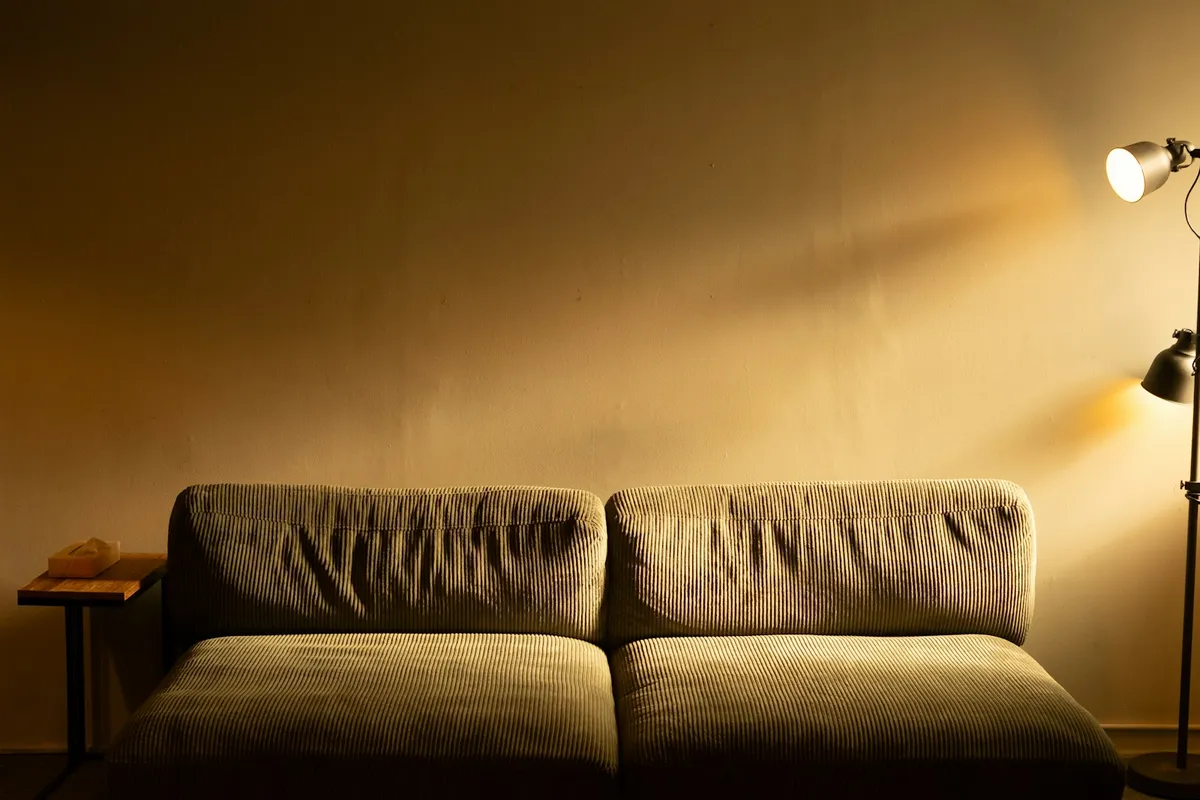 Living room sofa with a lit floor lamp and side table in the evening