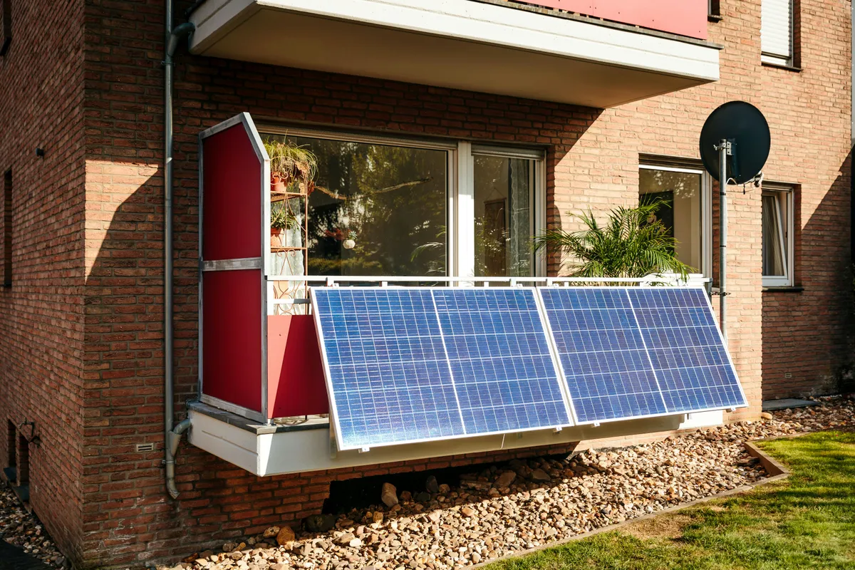 Plug-in solar panels mounted on an apartment balcony railing of a brick building