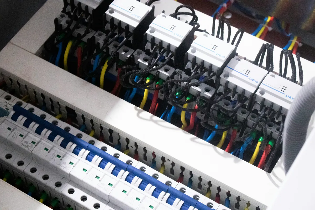 An open consumer unit showing rows of circuit breakers and coloured wiring