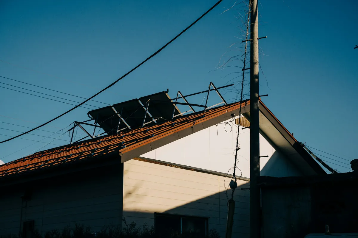 Solar panels on the tiled roof of a small house at sunset