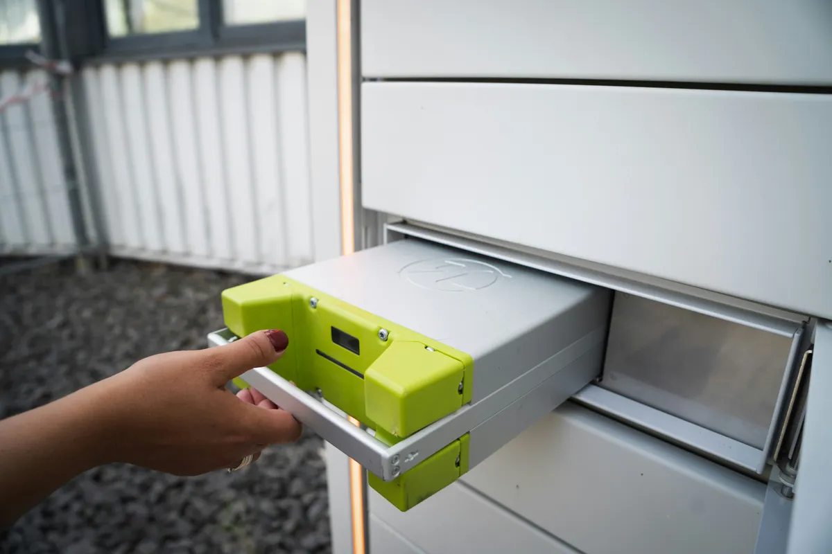 Modular home battery unit sliding into a metal storage rack