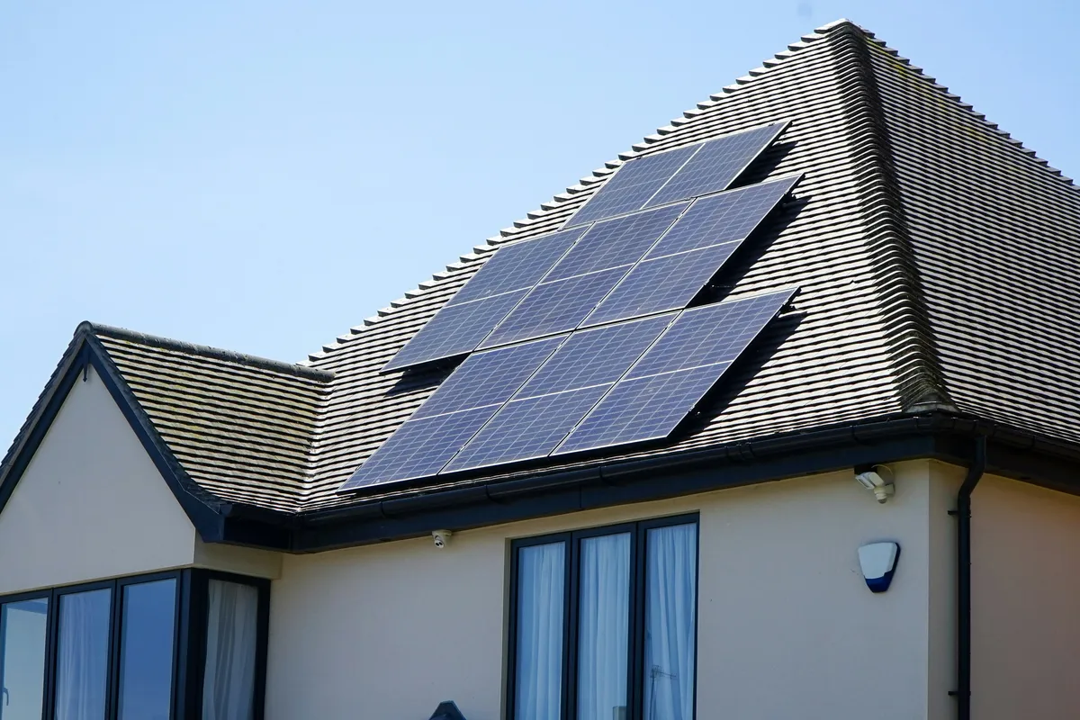 Residential home with a solar panel array mounted on a tiled roof under clear sky