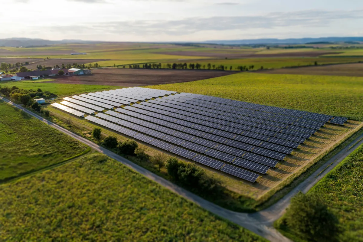 Ground-mounted panels spread across open grassland on a clear day