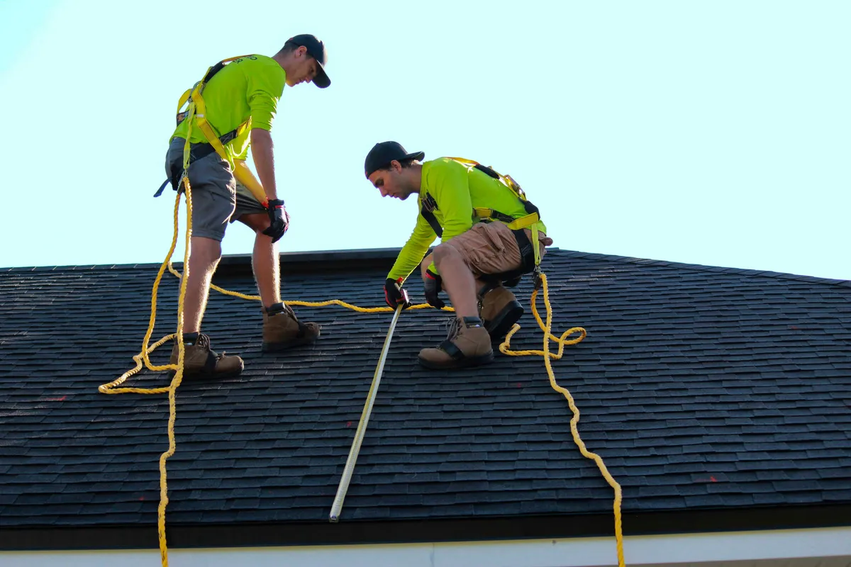 Two-person crew working a residential roof, the labour line on every quote