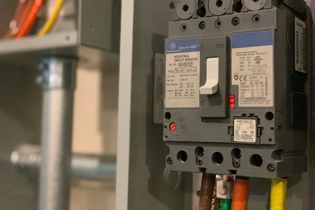 Three-pole circuit breaker with color-coded conductors mounted inside an electrical panel