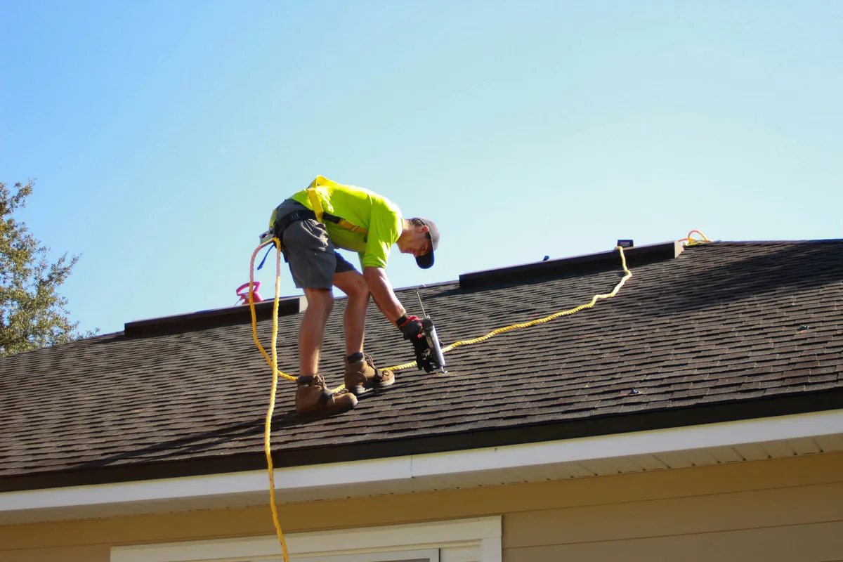 Installer driving mounting hardware into a roof with a cordless drill