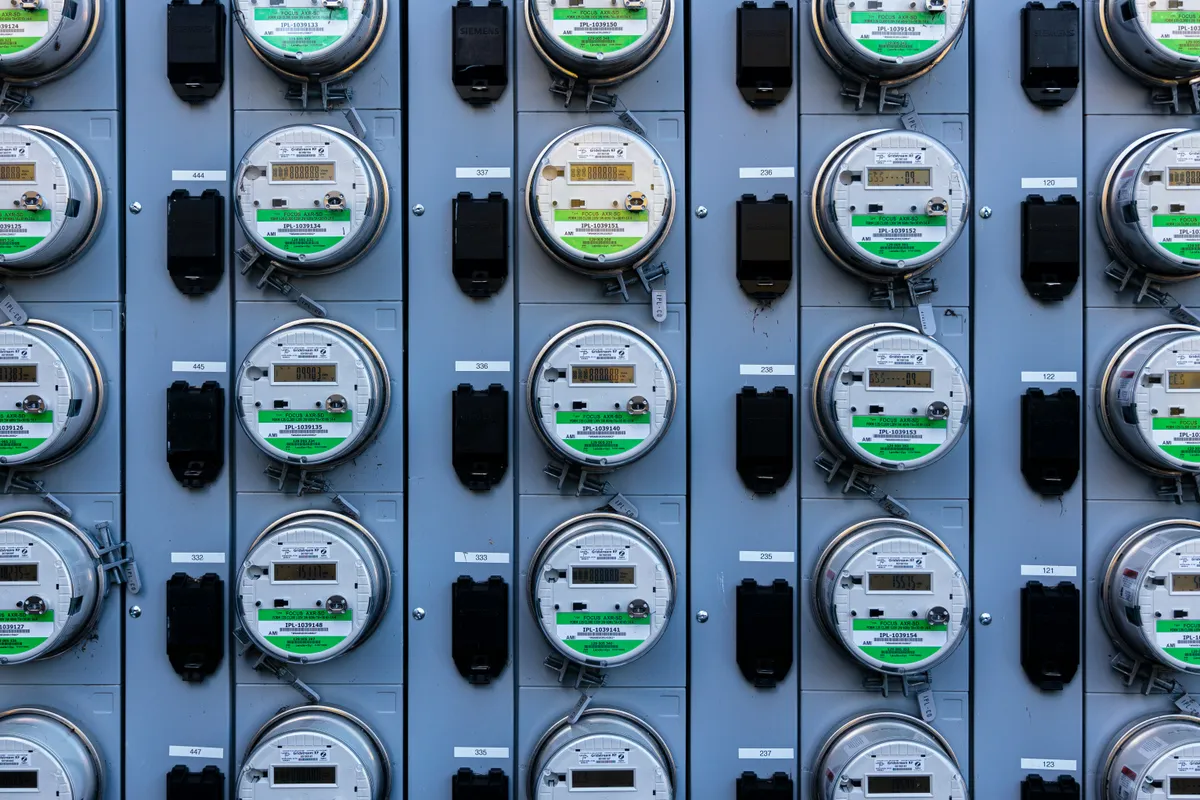 A wall of residential electricity meters in rows, each with a digital display
