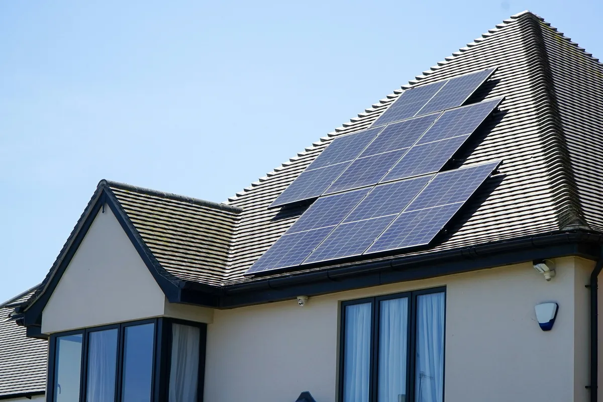 A two-storey house with a roof-mounted solar array under a clear sky